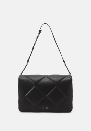 Sac porté épaule en cuir matelassé noir avec bandoulière réglable et petit logo « CK » sur le devant au centre.