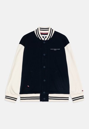 Sort og hvid Tommy Hilfiger varsity jakke med knaplukning, striped krave, manchetter og kant, samt logo på bryst og ærme.