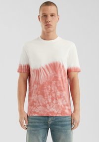 Witte t-shirt met korte mouwen en een gradient tie-dye in tinten van koraal, met een ronde halslijn en een zachte katoenen textuur.