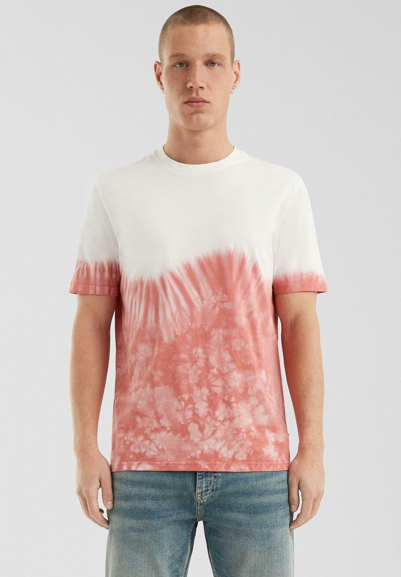Witte t-shirt met korte mouwen en een gradient tie-dye in tinten van koraal, met een ronde halslijn en een zachte katoenen textuur.