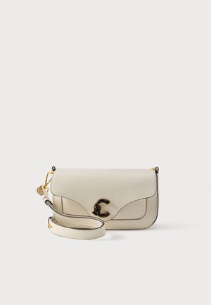 Bolso bandolera de cuero beige pálido con una solapa curva, herrajes dorados, un prominente logo C negro y una correa desmontable. Detalles de diseño sencillos.