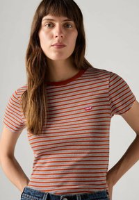 Camiseta de rayas rojas y blancas hecha de algodón, con un escote redondo y un pequeño parche con el logo de Levi's en el pecho izquierdo.