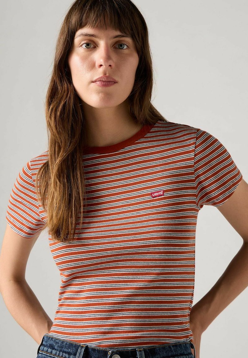 Camiseta de rayas rojas y blancas hecha de algodón, con un escote redondo y un pequeño parche con el logo de Levi's en el pecho izquierdo.