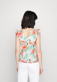 Blouse florale avec des manches courtes à volants, présentant un fond léger et des fleurs oranges vives avec des feuilles vertes, design en V au dos.