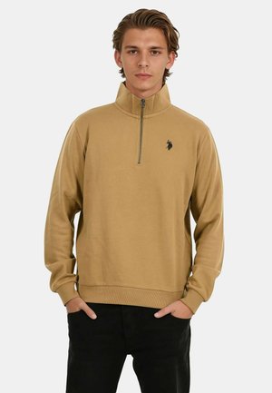 Beige Sweatshirt mit Viertelreißverschluss und hohem Kragen, gerippten Bündchen und kleinem schwarzem Logo auf der Brust, aus glattem Material gefertigt.