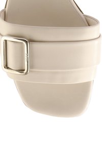 Beige sandal med en bred ovandel med en metallspänne, slät syntetisk material och en formad sula för komfort.
