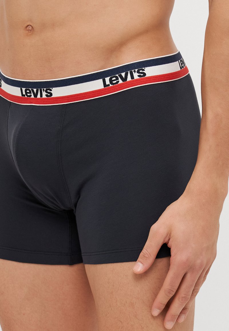 Sötétkék boxeralsó, mely szoros illeszkedésű, fehér derékpánttal, piros és sötétkék csíkokkal díszítve, és a "Levi's" logó jól láthatóan elhelyezve.