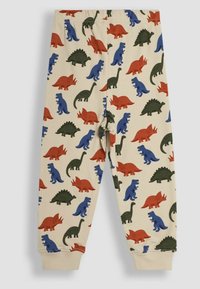 Pantalons en coton avec un fond crème, présentant des motifs de dinosaures colorés en rouge, bleu et vert. Taille élastique et poignets ajustés.
