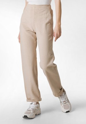 Beige high-waisted trousers with a smooth texture, featuring side pockets and a straight-leg cut, paired with white athletic sneakers.