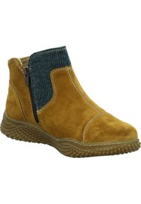 Beiger Wildleder-Ankle-Boot mit einem gerippten tealfarbenen Elastikpaneel, seitlichem Reißverschluss und texturiertem Gummisohle. Kontrastnähte betonen das Design.