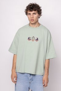 tricou din bumbac oversize de culoare verde deschis, cu un design brodat central ce include elemente florale și abstracte. Mâneci scurte și croială lejeră.