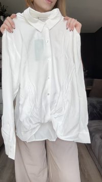 White, long-sleeve button-up shirt featuring a collar, a knotted front detail, smooth texture, and a relaxed fit.