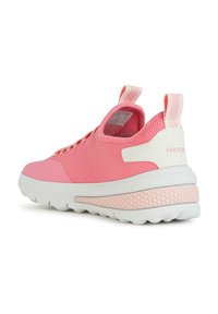 Zapatilla de malla rosa con un panel trasero blanco, suela texturizada y acentos en rosa. Cuenta con cordones elásticos y una lengüeta en la parte posterior.