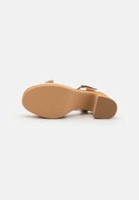 Wedge sandal with a light brown suede upper, textured cork platform, and a solid rubber sole. Features a small heel and adjustable strap.
