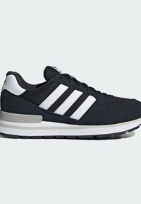 Baskets Adidas noir et blanc avec trois bandes blanches, dessus en mesh et daim, et semelle rembourrée sur fond neutre.