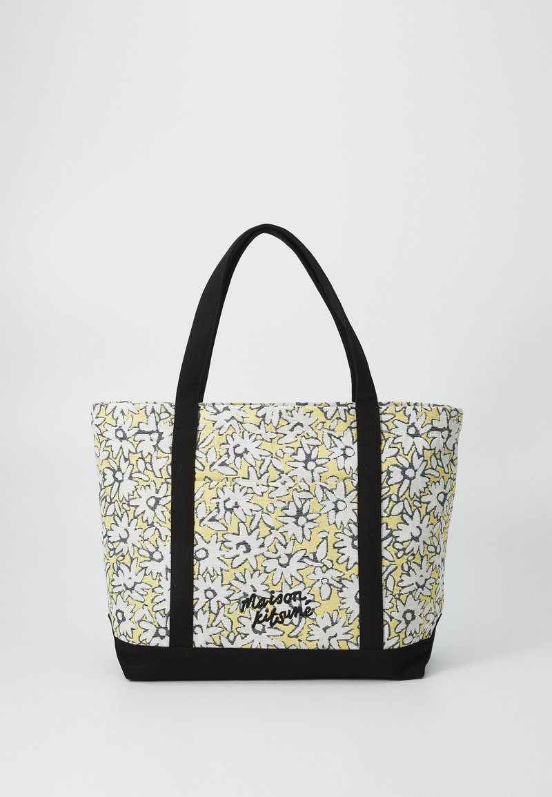 Bolsa tote con patrón floral amarillo y negro, asas de tela negra y base negra, con bordado de la marca en el lateral.
