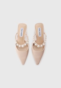 Μπεζ πάνινα ψηλοτάκουνα παπούτσια με πίσω λουράκι και μυτερή μύτη, διακοσμημένα με λουράκι που έχει ανάγλυφες πέρλες. Λείο υλικό και μινιμαλιστικός σχεδιασμός.