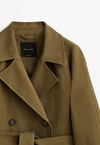 Manteau marron croisé à larges revers, boutons noirs, ceinture assortie et étiquette noire indiquant « Massimo Dutti ».
