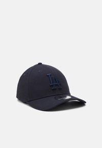 Casquette de baseball bleu marine en tissu, arborant un logo "LA" brodé de la même couleur, une visière courbée et une sangle ajustable à l'arrière.