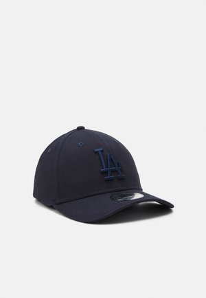 Gorra de béisbol azul marino de tela, con un logotipo bordado "LA" en color a juego, visera curvada y correa ajustable en la parte posterior.