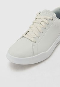 Baskets blanches en cuir lisse, avec des lacets plats, un col rembourré et une doublure intérieure texturée, dotées d'un design de bout arrondi.
