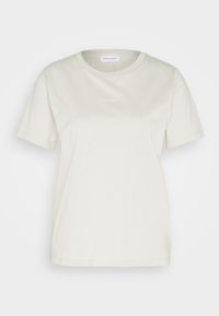 T-shirt a maniche corte, collo girocorta in cotone color avorio. Presenta un piccolo logo Calvin Klein centrato, dello stesso colore, con una texture liscia.
