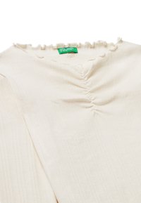 Gestreiftes Elfenbeinoberteil mit rüschigem Ausschnitt und zentralem Raffungsdetail. Es verfügt über ein grünes Etikett mit dem Text "United Colors of Benetton".