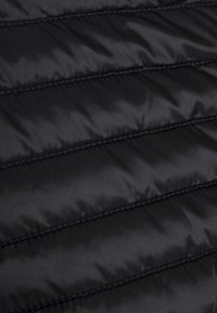 Schwarzer gepolsterter Stoff mit vertikalen Steppnähten. Das Material wirkt glänzend und hat eine glatte Textur. Die Nähte sind entlang der Säume sichtbar.