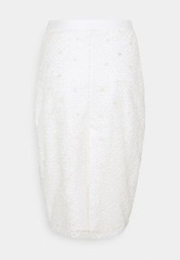 Jupe crayon blanche présentant un motif texturé à pois avec de petites accents en relief. Ceinture blanche simple, coupe ajustée.