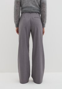 Wijdvallende broek van een gestructureerde lichtgrijze stof, met een hoge taille, voorplooien en een enkele achterzak.