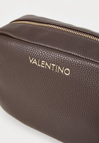 Borsa in pelle marrone con texture e zip dorata. Presenta il nome del marchio "VALENTINO" in rilievo e in oro sulla parte frontale. Design rettangolare.