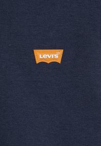 Navyblauwe stof met een gladde textuur, voorzien van een oranje gestikt Levi's logo in een driehoekige vorm in het midden.