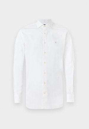 Witte blouse met lange mouwen van katoen. Voorzien van een knoopsluiting aan de voorkant, een puntige kraag en een klein blauw geborduurd logo op de borst.