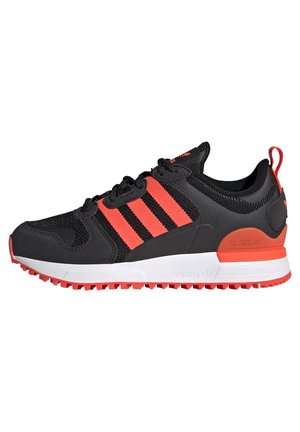 Sneaker nera con tre strisce orizzontali rosse, upper in mesh testurizzato, intersuola bianca imbottita e suola in gomma rossa.