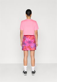 Ροζ κοντομάνικο t-shirt συνδυασμένο με πολύχρωμη φλοράλ φούστα που έχει μεγάλα ροζ και πορτοκαλί άνθη. Μαύρα παπούτσια και λευκές κάλτσες ολοκληρώνουν την εμφάνιση.