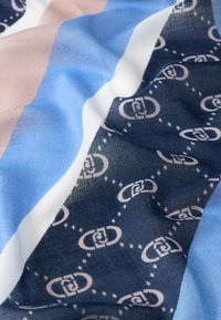 Tessuto multicolore con strisce diagonali in blu, rosa e bianco, caratterizzato da un motivo blu navy di forme collegate e dettagli a pallini.