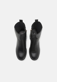 Paire de bottines en cuir noir avec fermetures éclair latérales et languettes, vue de dessus sur un fond blanc uni.