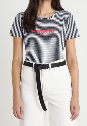 Bawełniany t-shirt w paski w kolorze granatowym i białym z czerwonym nadrukiem „bonjour”, zestawiony z białymi dżinsami i czarnym skórzanym paskiem.