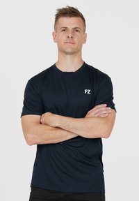 Marinblå atletisk t-shirt med korta ärmar, rund halsringning och vitt "FZ"-logotyp. Lätt och slätt tyg med en figurnära passform.