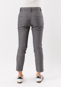 Pantaloni grigi a quadri con vestibilità su misura, caratterizzati da due tasche posteriori, gambe affusolate e una texture liscia. Indossati con sneakers bianche.