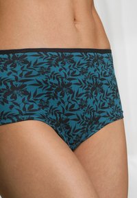 Slip in cotone elasticizzato di colore teal con stampa floreale e vita nera. Presenta motivi a foglia e una texture liscia. Design leggermente a vita alta.