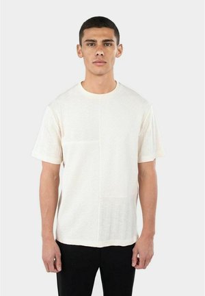 Kortärmad, krämfärgad t-shirt i texturerat tyg med två distinkta paneldesigns och rundad halsringning.