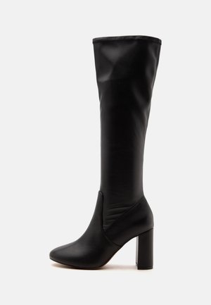 Botte noire pour femme montant jusqu'au genou, avec bout arrondi et talon bloc sur fond blanc.