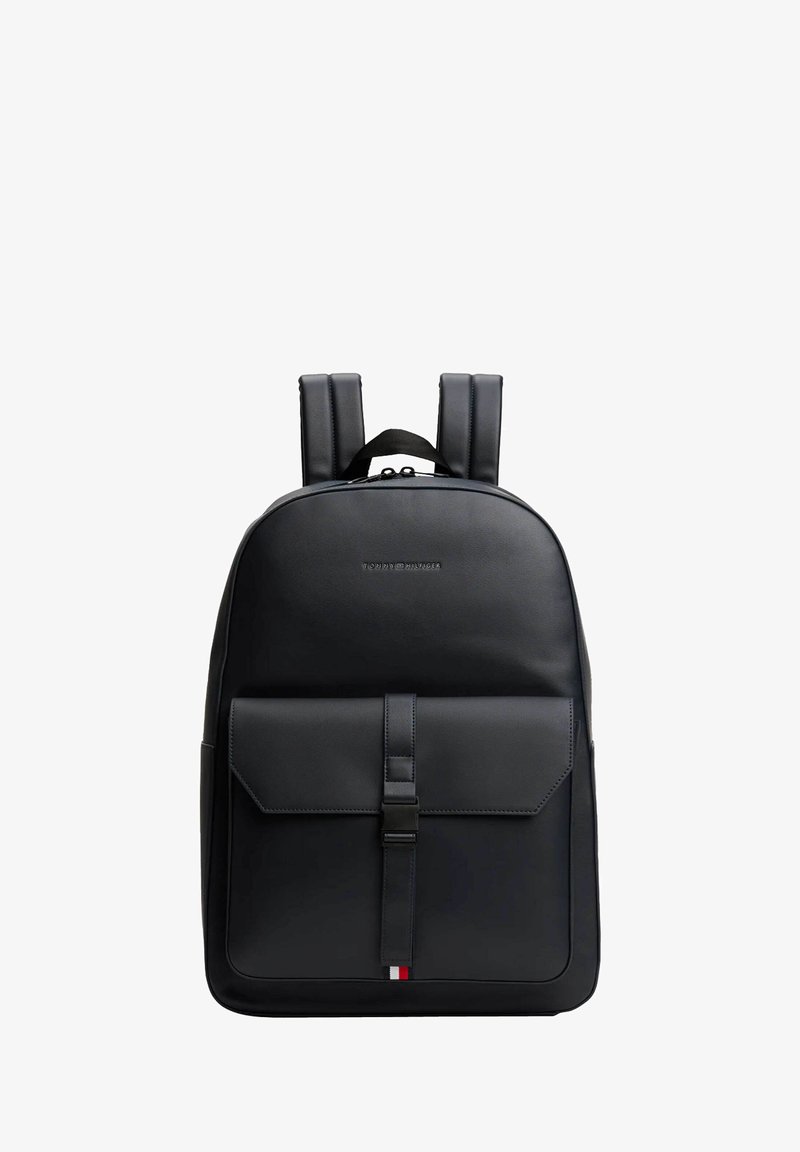 Zaino in pelle nera con spallacci imbottiti, tasca frontale a patta chiusa da una fascetta e piccolo logo tricolore come dettaglio nella parte inferiore.