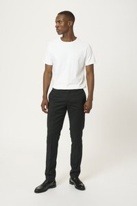 T-shirt en coton blanc associé à un pantalon noir ajusté et des chaussures en cuir noires. Design slim-fit avec un col rond et une texture lisse.