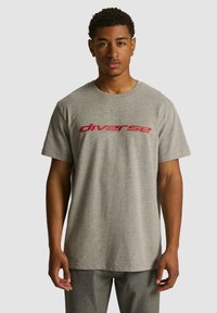 Szara bawełniana koszulka z krótkim rękawem z czerwonym napisem "diverse" na klatce piersiowej. Okrągły dekolt i luźny krój.