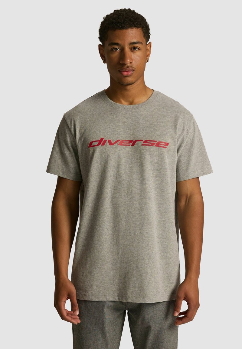 Szara bawełniana koszulka z krótkim rękawem z czerwonym napisem "diverse" na klatce piersiowej. Okrągły dekolt i luźny krój.
