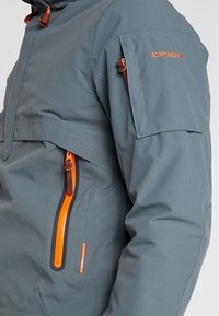 Veste de pluie légère et grise avec des zips orange, des accents de poche et un col haut. Texture lisse, caractéristiques ajustables pour un meilleur ajustement.