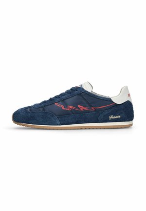 Marineblå sneakers med ruskind og nylonpaneler, rødt abstrakt side-design, hvid hæl-flig og "France" broderet nær sålen.