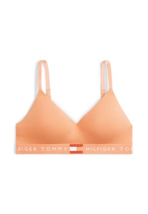 Zacht perzikkleurige draadloze beha met verstelbare bandjes en een elastische band met het merk "Tommy Hilfiger" in witte letters.